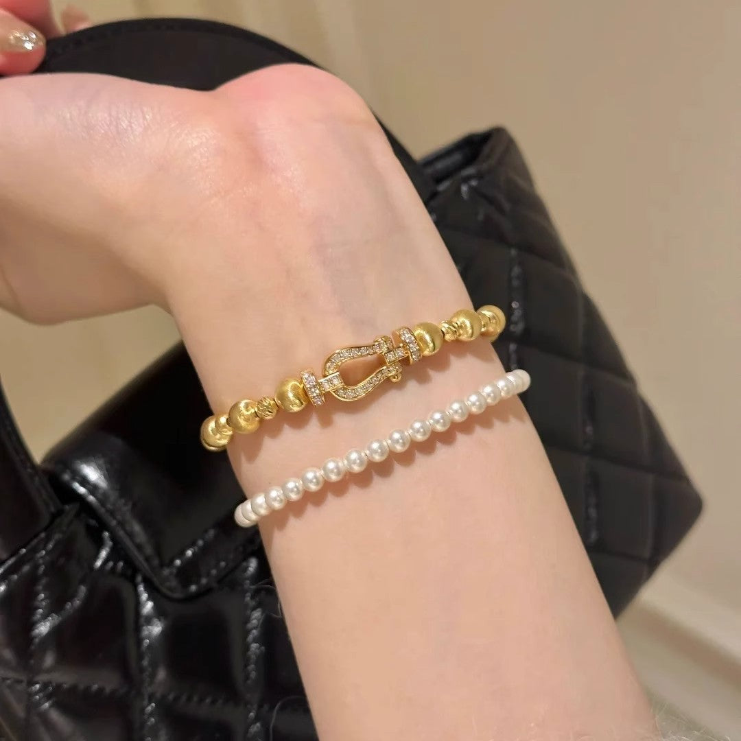 Gold-tone bracelet on wrist; pearl bracelet not included