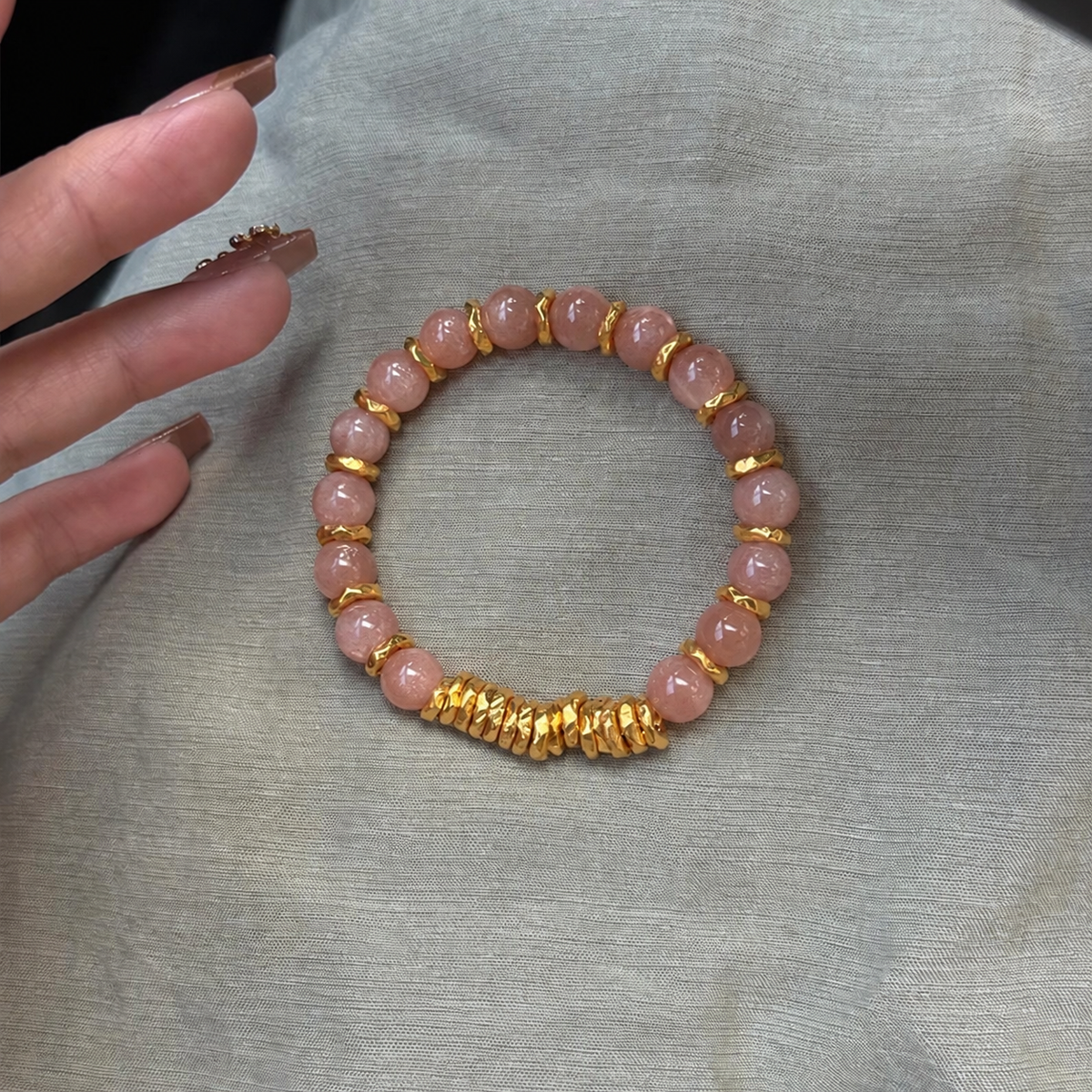 Pink sunstone bracelet showing round beads and gold-tone spacers