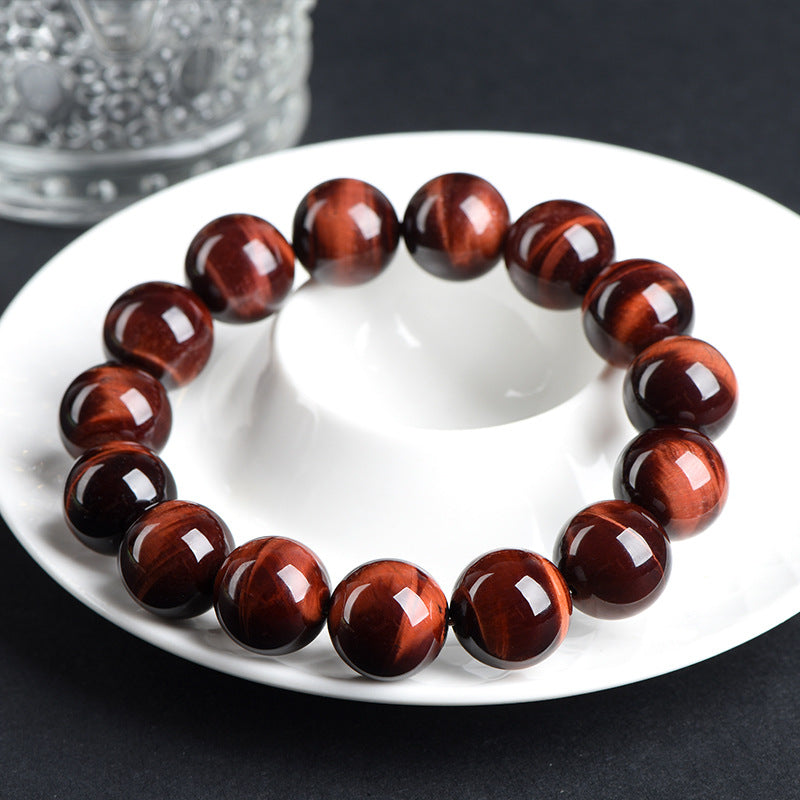 Red tiger’s eye bracelet resting on a white saucer