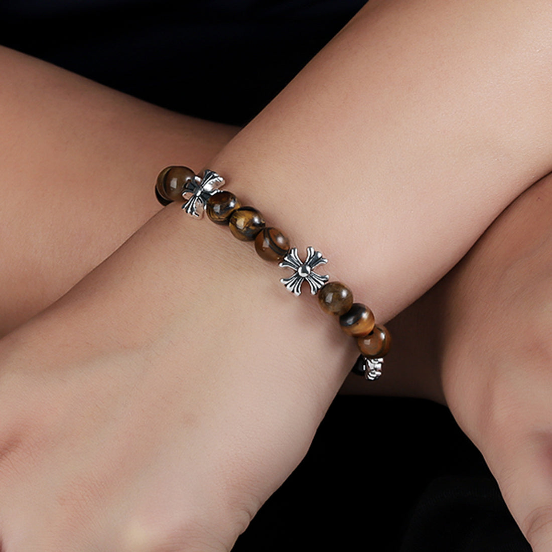 Cross accent tiger eye bracelet worn on a wrist