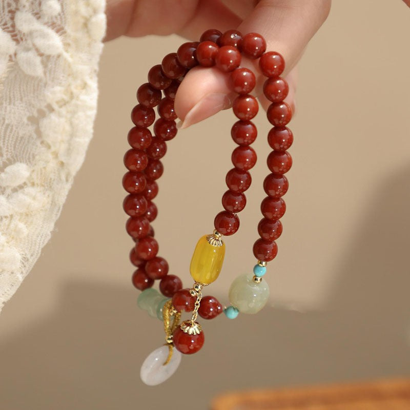 Red agate double-wrap bracelet showing peace disc and dangling bead