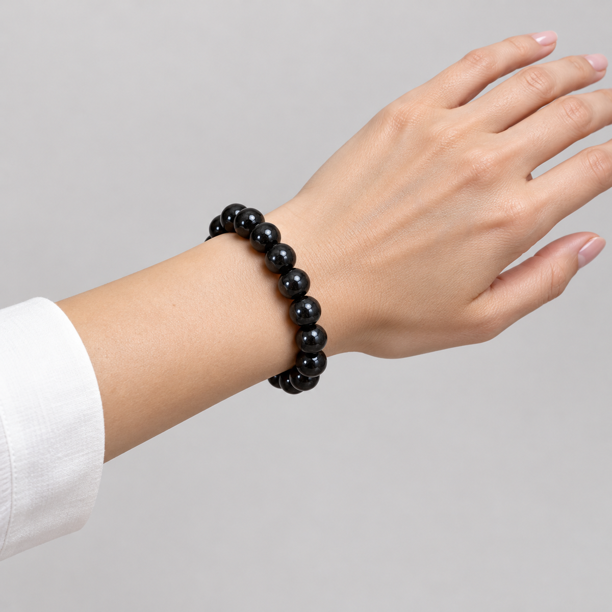 Black tourmaline bracelet worn on one wrist with a white shirt cuff