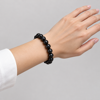 Black tourmaline bracelet worn on one wrist with a white shirt cuff
