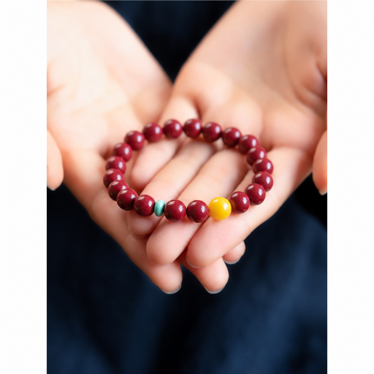 Red bead bracelet with blue-green disc and yellow accent in hands