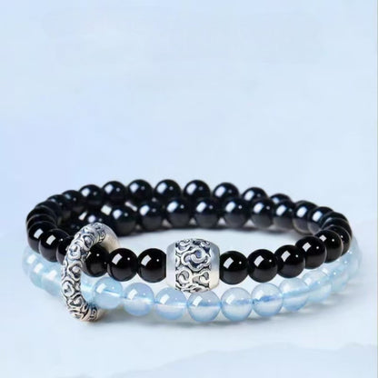 Double-wrap bracelet showing black and icy blue beads with ornate cloud-pattern accents