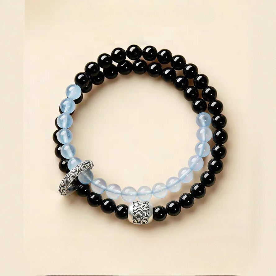 Double-wrap bracelet showing black and icy blue beads with ornate cloud-pattern accents