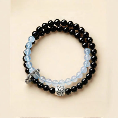 Double-wrap bracelet showing black and icy blue beads with ornate cloud-pattern accents