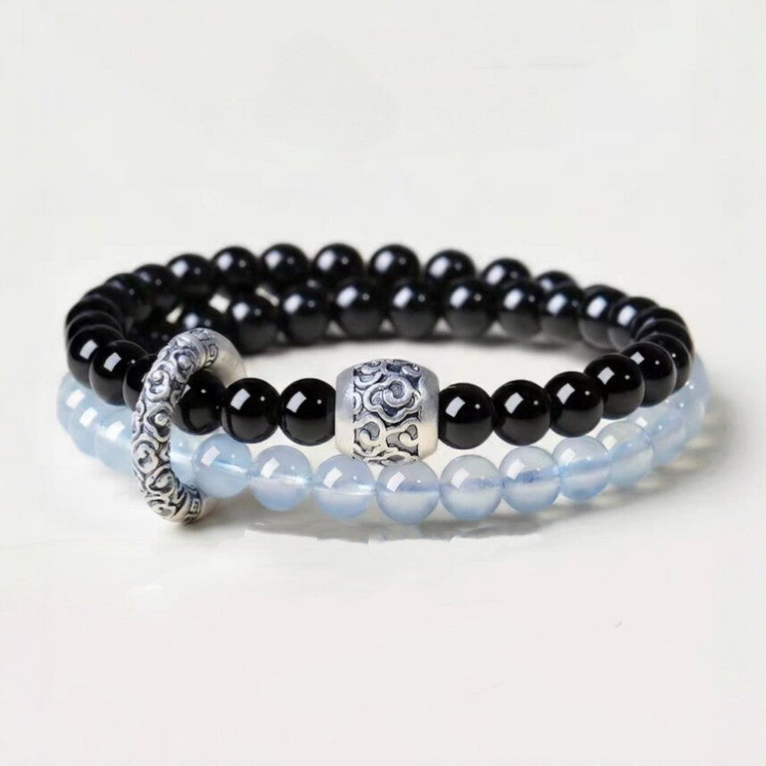 Double-wrap bracelet showing black and icy blue beads with ornate cloud-pattern accents