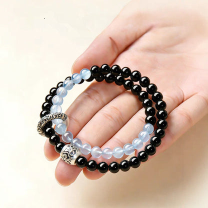 Double-wrap bracelet showing black and icy blue beads with ornate cloud-pattern accents