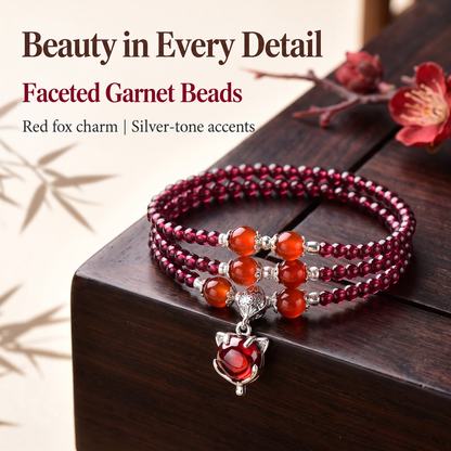 Garnet triple-wrap bracelet showing orange-red accents and silver-tone fox charm on dark wood