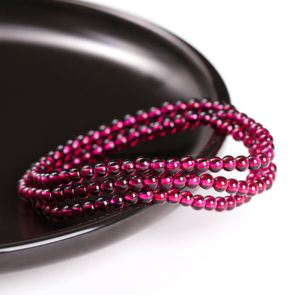 Wine-red garnet triple-wrap bracelet on a dark surface