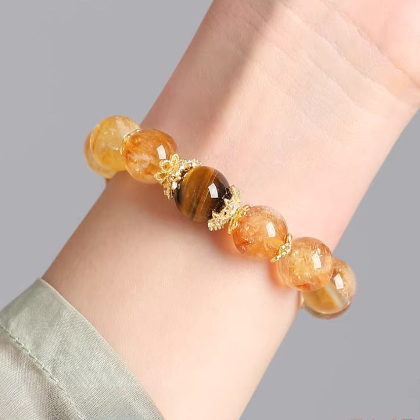 Golden crystal and tiger eye bracelet worn on a wrist