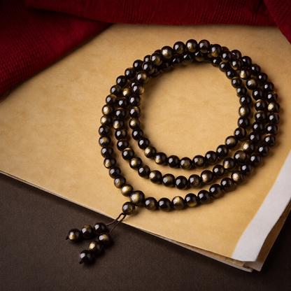 Polished golden sheen obsidian bracelet resting on a book