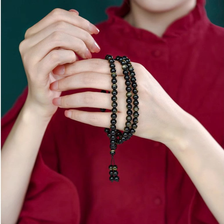 Golden sheen obsidian multi-wrap bracelet held in hands