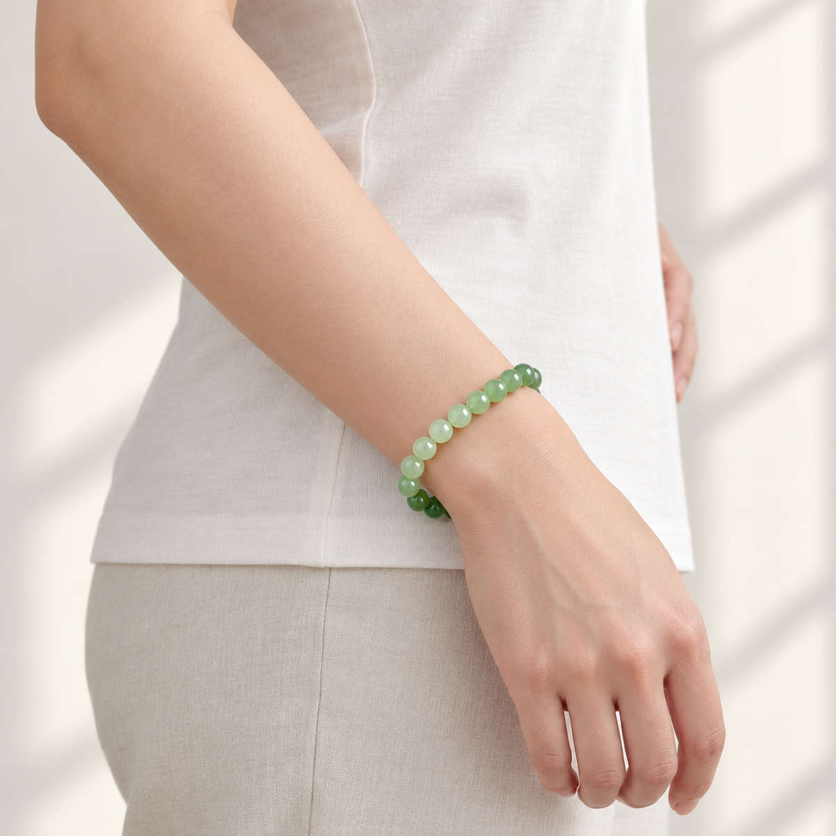 Gradient green Hetian jade bracelet worn with a white top, side view