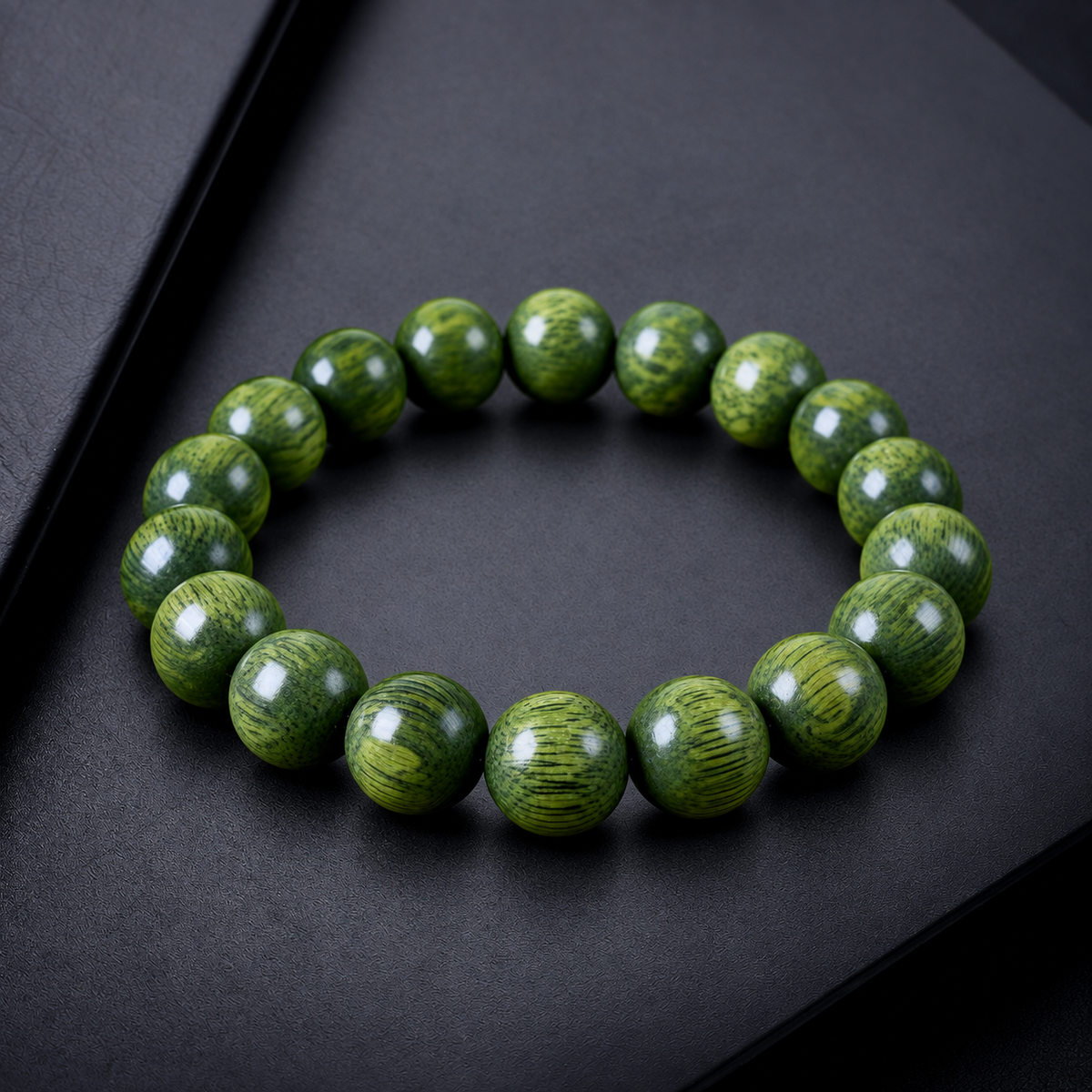 Green sandalwood bead bracelet displayed on charcoal surface