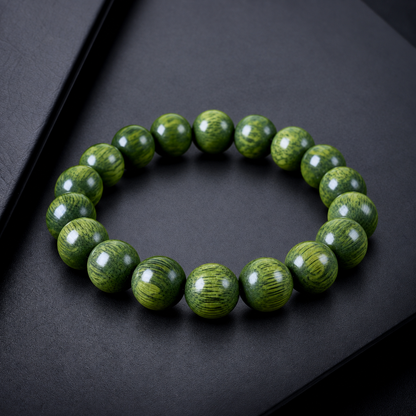 Green sandalwood bead bracelet displayed on charcoal surface