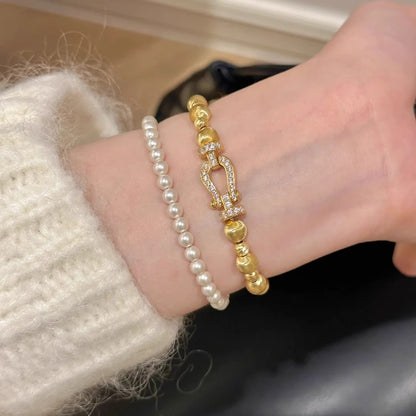 Gold-tone bracelet styled with a separate pearl bracelet