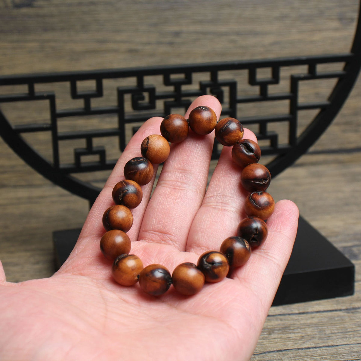 12mm jujube wood bracelet held in a hand showing grain and dark fissures