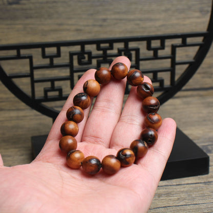 12mm jujube wood bracelet held in a hand showing grain and dark fissures