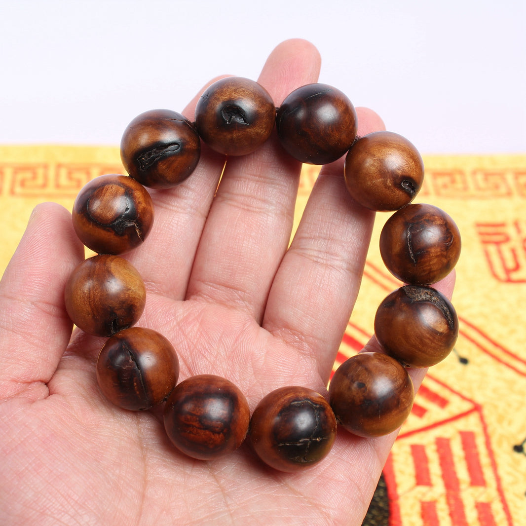 Jujube wood beads with dark patches and fissures shown on a hand