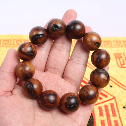 Jujube wood beads with dark patches and fissures shown on a hand