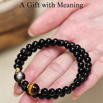 Obsidian and tiger eye double-wrap bracelet held in a hand