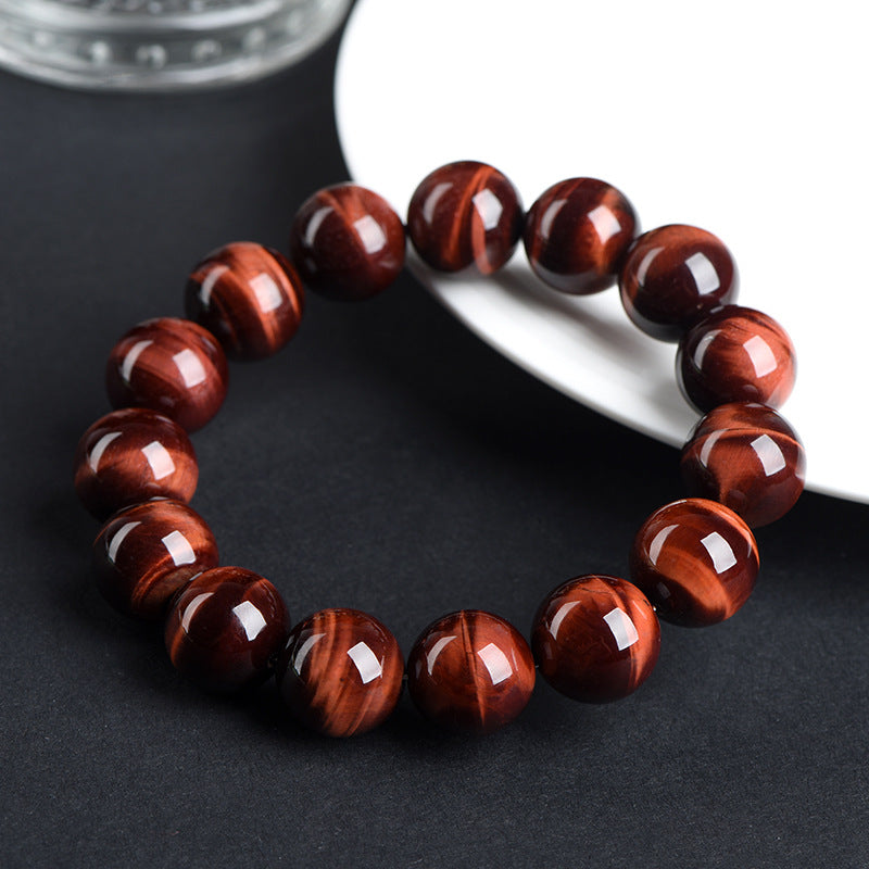 Red tiger’s eye bracelet beside a white plate