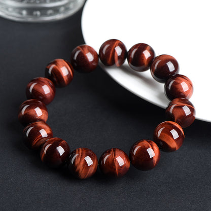Red tiger’s eye bracelet beside a white plate