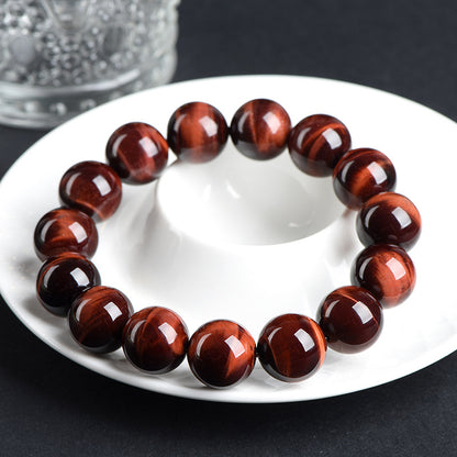 Red tiger’s eye bracelet resting on a white saucer