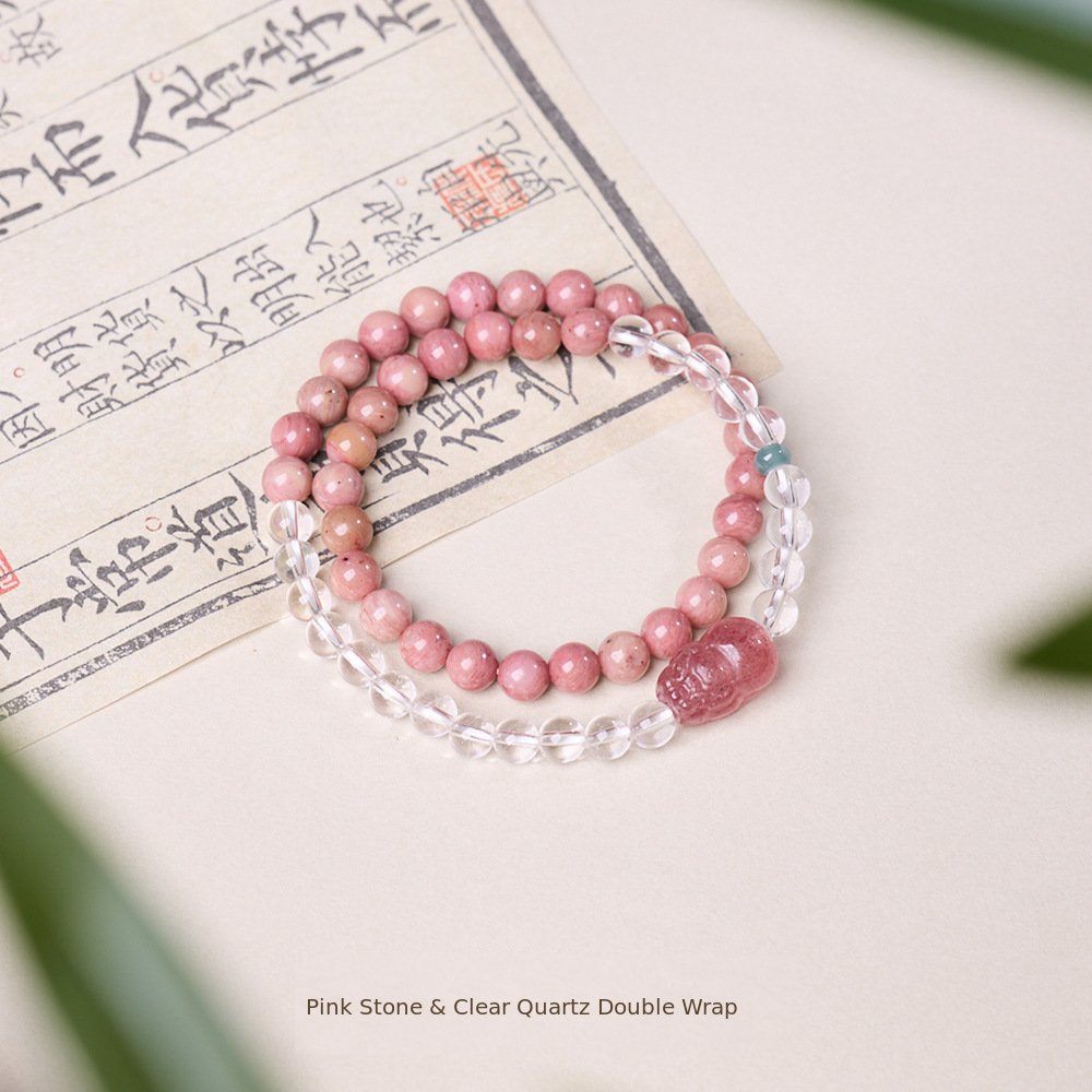 Double-wrap pink stone and clear quartz bracelet on calligraphy paper
