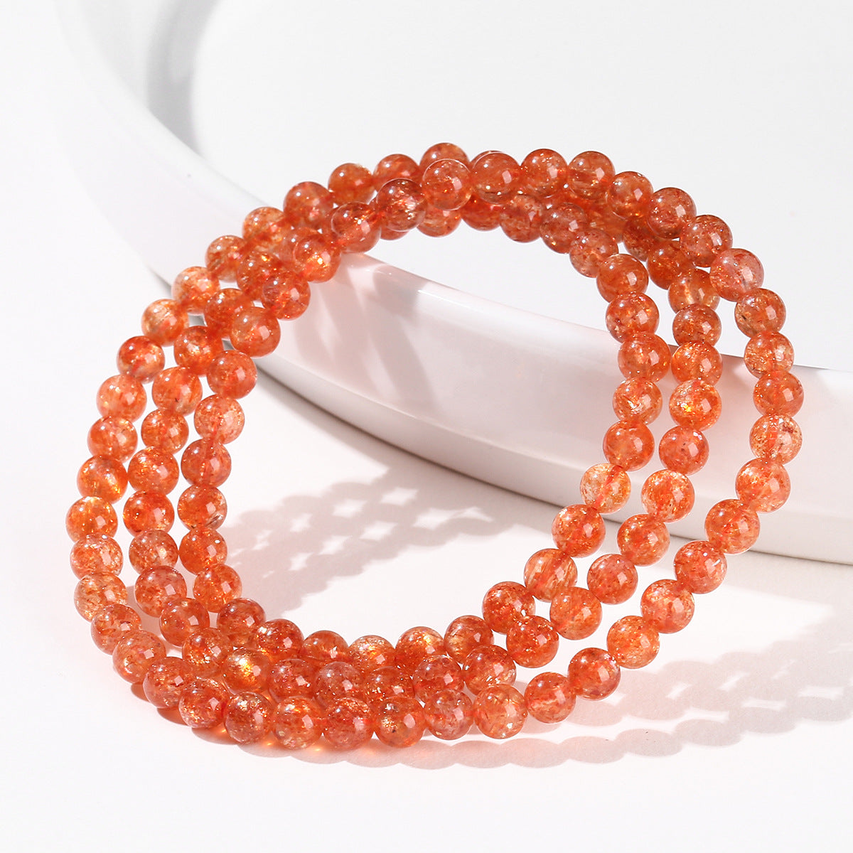 Sunstone triple-wrap bracelet displayed on white ceramic