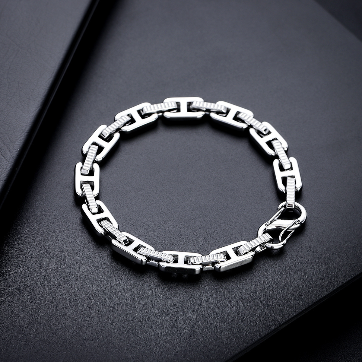 Textured silver-tone H-link bracelet displayed on a black background