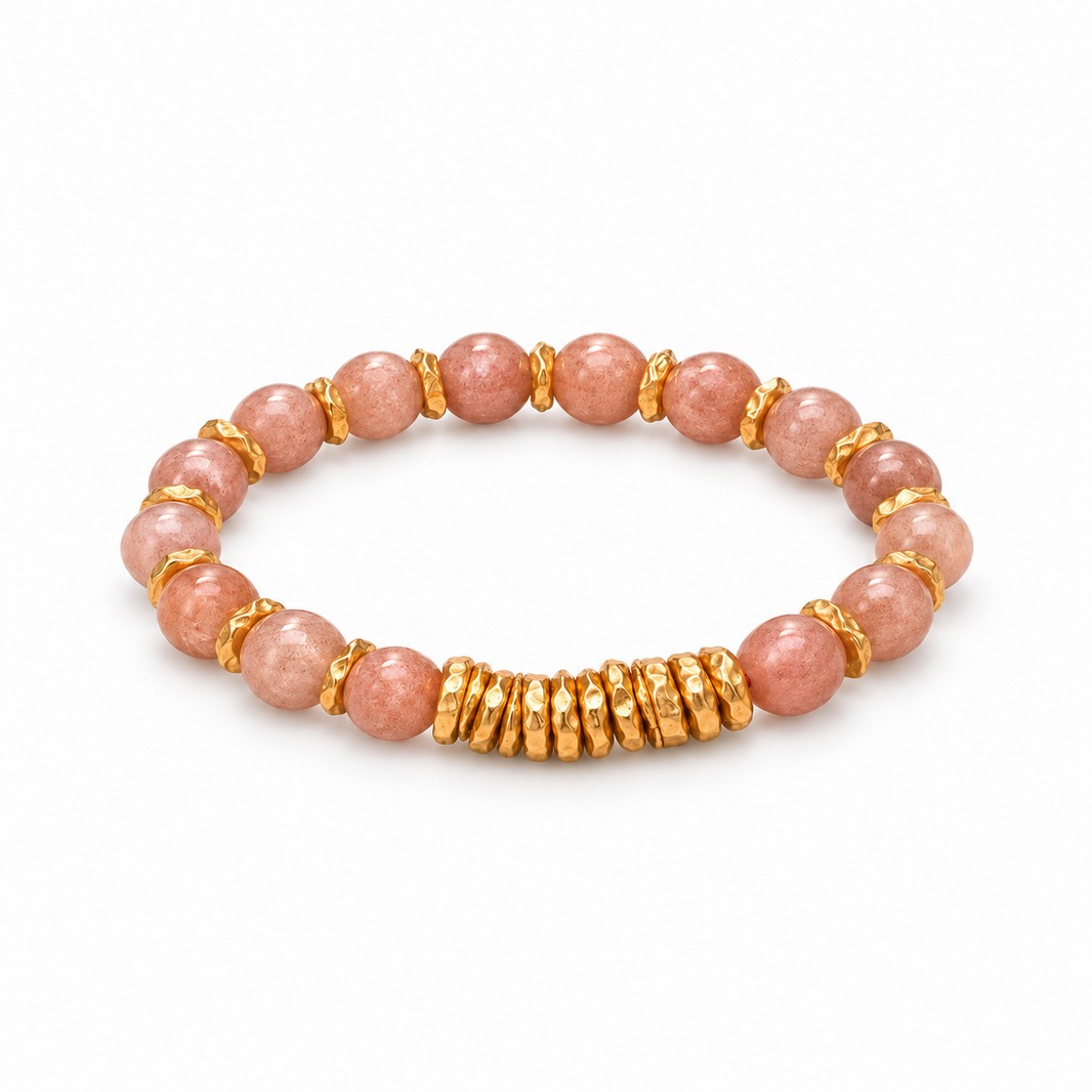 Pink sunstone bead bracelet with gold-tone spacers and stacked disc accents on white