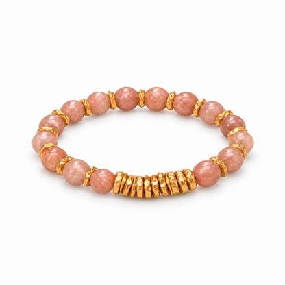 Pink sunstone bead bracelet with gold-tone spacers and stacked disc accents on white