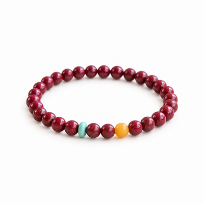 Burgundy red bead bracelet with turquoise-colored disc and yellow accent bead on white