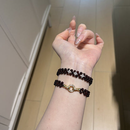 Woven garnet bracelet worn with floral accents and clasp visible