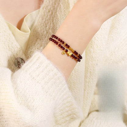 Garnet double-wrap bracelet worn with a cream knit sleeve