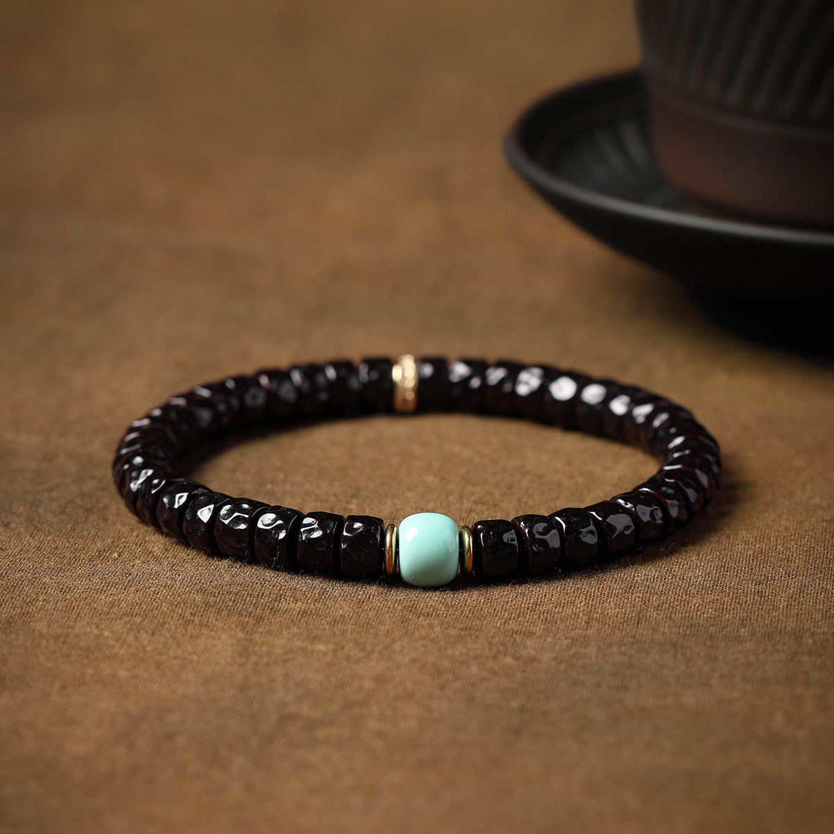 Dark sculpted coconut-pedicel beads with blue centerpiece and gold-tone spacers