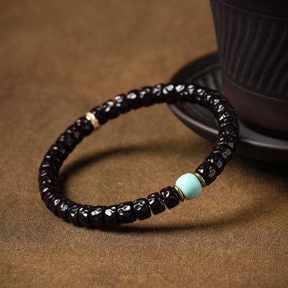 Angled view of sculpted coconut-pedicel bracelet and blue accent
