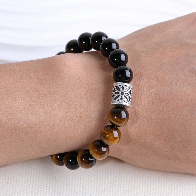 Tiger eye and obsidian bracelet with silver floral accent worn on a wrist