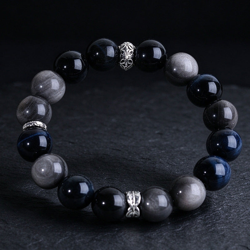 Blue tiger eye and silver-sheen obsidian bracelet with silver-tone spacers on a dark surface