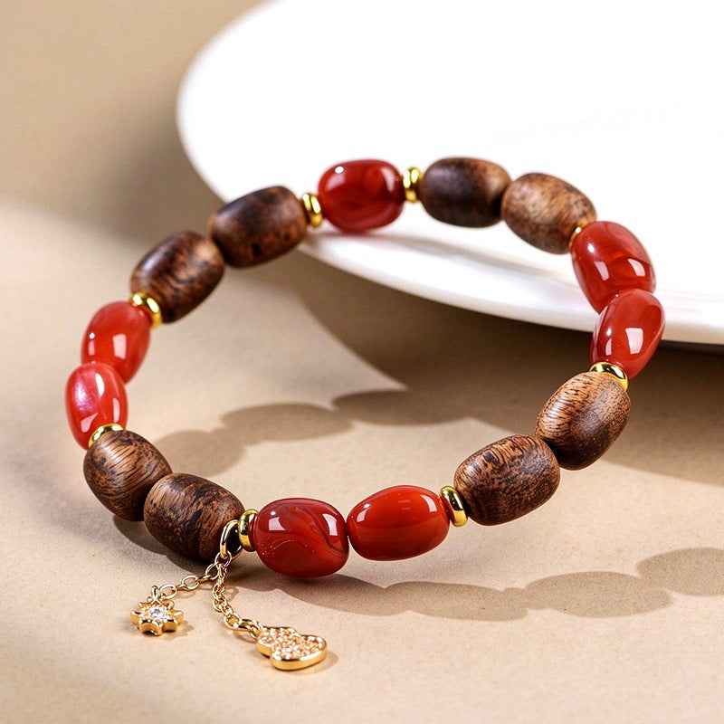 Red agate and agarwood barrel beads with gold-tone spacers and charms
