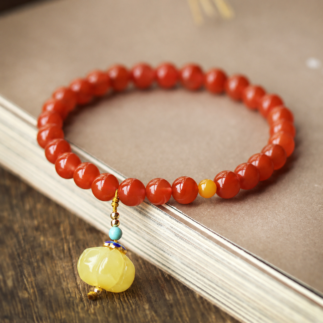 Red agate bracelet and amber pumpkin charm on a book