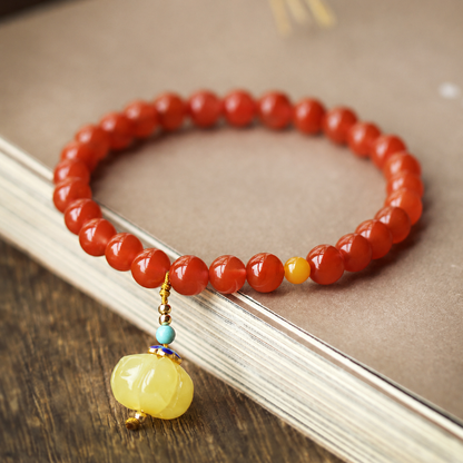 Red agate bracelet and amber pumpkin charm on a book