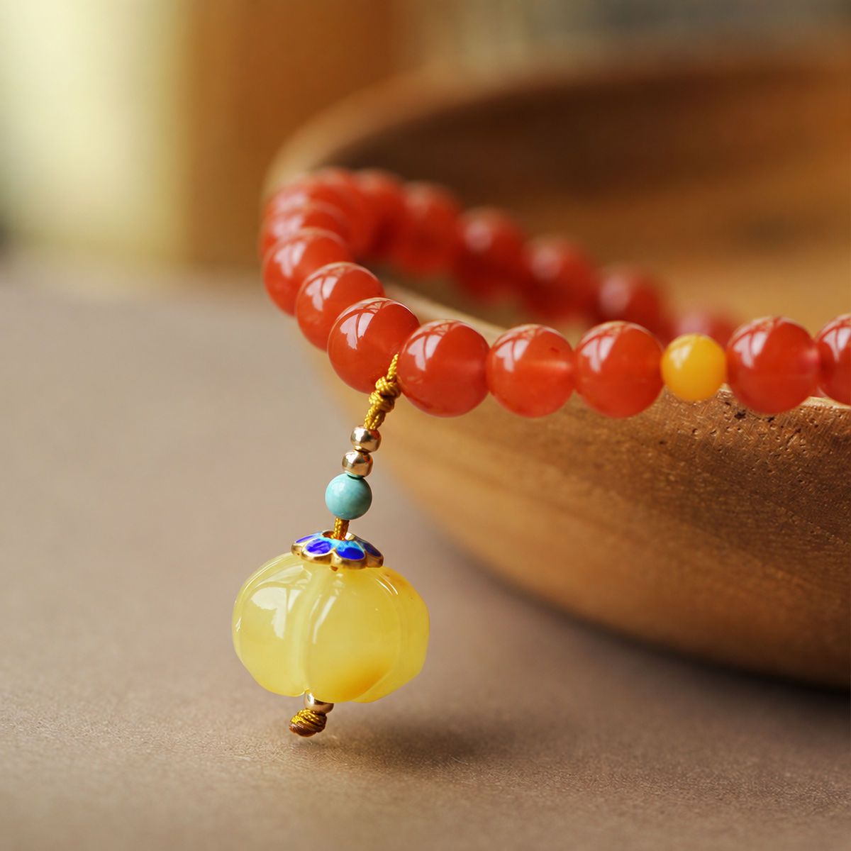Close view of yellow amber pumpkin charm and blue decorative cap