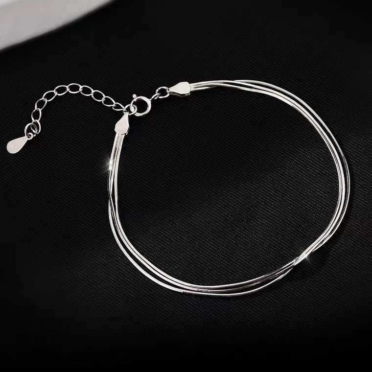 S925 triple-strand snake chain bracelet on dark fabric