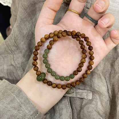Seed bead bracelet with olive jade beads and running ring on a linen tray