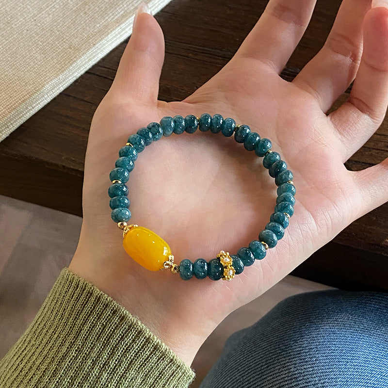Teal chalcedony bracelet and yellow agate centerpiece held in hand