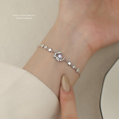 Wrist styling of silver whale bracelet with luminous blue glass